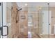 Elegant walk-in shower featuring decorative stone tile, glass enclosure, and a handheld shower head at 5115 Amberden Hall Dr, Suwanee, GA 30024