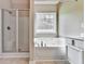 Bathroom featuring a glass-enclosed shower and jacuzzi tub beneath a bright window at 114 Saddle Wood Dr, Dallas, GA 30157