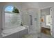 Elegant bathroom featuring a soaking tub under a decorative window and a glass-enclosed shower at 8630 Moor Park Run, Duluth, GA 30097