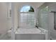 Bathroom with a soaking tub beneath an arched window and a glass-enclosed shower with modern fixtures at 8630 Moor Park Run, Duluth, GA 30097
