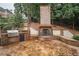 Outdoor kitchen with stainless steel grill and brick fireplace on a stone patio at 8630 Moor Park Run, Duluth, GA 30097