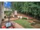 Outdoor dining and kitchen space with a fireplace and BBQ, surrounded by landscaped gardens at 8630 Moor Park Run, Duluth, GA 30097
