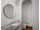 Elegant powder room featuring a granite countertop, round mirror, and a toilet inside an arched alcove at 8630 Moor Park Run, Duluth, GA 30097