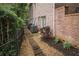 Stone pathway leading along the side of a brick home, with mature trees and landscaping at 8630 Moor Park Run, Duluth, GA 30097
