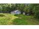 A detached garage sits adjacent to a shed in a large backyard surrounded by mature trees at 2026 Mcdaniel Mill Sw Rd, Conyers, GA 30094