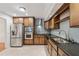 Kitchen with stainless steel appliances, wood cabinetry, black countertops and tiled backsplash at 1416 Oakridge Cir, Decatur, GA 30033