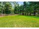Spacious backyard with lush greenery, a charming wooden fence, and a cute red shed for storage at 1978 Elmwood Cir, Snellville, GA 30078