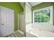 Green bathroom featuring a white bathtub, separate shower and a window with bright, natural light at 1978 Elmwood Cir, Snellville, GA 30078