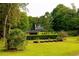 Lush backyard with manicured landscaping, providing a private retreat with mature trees and charming house view at 8601 Flint Hill Rd, Douglasville, GA 30135