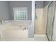 Bright bathroom featuring a large bathtub, glass block window and a shower at 8601 Flint Hill Rd, Douglasville, GA 30135