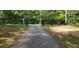 Long paved driveway leading to gated property with wooded surroundings and black wooden fencing at 8601 Flint Hill Rd, Douglasville, GA 30135