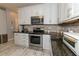 Modern kitchen with stainless steel appliances, white cabinetry, granite counters, and sleek tile flooring at 8601 Flint Hill Rd, Douglasville, GA 30135