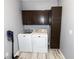 Functional laundry room with washer, dryer, dark cabinets, and wood-look flooring at 8601 Flint Hill Rd, Douglasville, GA 30135