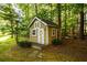 Charming outdoor storage shed with a decorative door, surrounded by lush greenery and a well-manicured lawn at 1304 Carrington Way, Lawrenceville, GA 30044