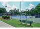 Tennis court surrounded by lush green lawn featuring seating and mature trees for shade at 1304 Carrington Way, Lawrenceville, GA 30044
