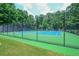 Well-maintained tennis court surrounded by mature trees and lush green lawn at 1304 Carrington Way, Lawrenceville, GA 30044