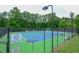 View of the community's well maintained tennis court, fully fenced in and set amongst mature trees at 1304 Carrington Way, Lawrenceville, GA 30044