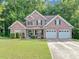 Traditional brick home featuring a well-manicured lawn, manicured bushes, and a two-car garage at 4375 Split Creek Dr, Douglasville, GA 30135