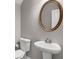 Clean and simple half bath with a pedestal sink, round mirror, and neutral decor at 4204 Hardy Ave, Smyrna, GA 30082