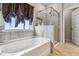Bright bathroom featuring a soaking tub, tiled walls, and glass enclosed shower at 6094 Whitetail Deer Run, Mableton, GA 30126