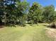Expansive backyard featuring a large green lawn, mature trees, and a charming back deck at 2266 Eastgate Dr, Snellville, GA 30078