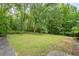 This grassy backyard surrounded by mature trees offers a serene outdoor space at 4025 Cheoah Dr, Douglasville, GA 30135