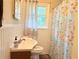 Bright bathroom featuring a classic sink, toilet, and floral shower curtain at 5167 Hiram Lithia Springs Rd, Powder Springs, GA 30127