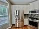 Corner kitchen featuring stainless steel appliances, granite countertops, modern lighting, and white cabinets at 3988 Church View Ln, Suwanee, GA 30024