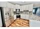 Updated kitchen featuring stainless steel appliances, granite countertops, white cabinets, and hardwood floors at 3988 Church View Ln, Suwanee, GA 30024