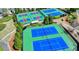 Aerial view of community tennis courts with vibrant blue and red surfaces, surrounded by trees at 3988 Church View Ln, Suwanee, GA 30024