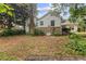 Rear exterior view shows siding, brick, and chimney in a grassy and partially wooded yard at 5128 Lavista Rd, Tucker, GA 30084