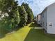 A lush green backyard featuring an expansive lawn, mature trees and a concrete patio at 5909 Rue Chase Way, Tucker, GA 30084