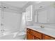 Bathroom with white tiled shower and tub combination, and a cherry vanity at 5909 Rue Chase Way, Tucker, GA 30084
