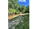 Tranquil creek with sandy bank, surrounded by lush greenery and mature trees at 6675 Millwood Rd, Cumming, GA 30041