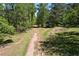 Outbuilding alongside a dirt driveway is surrounded by trees and lush greenery at 6675 Millwood Rd, Cumming, GA 30041