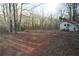 Outbuilding with white paneling is surrounded by tall bare trees and dead leaves at 6675 Millwood Rd, Cumming, GA 30041