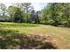 Open yard with lush green grass and scattered trees, offering space for outdoor activities at 6675 Millwood Rd, Cumming, GA 30041