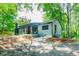 Quaint exterior view of home with a covered porch, gray siding, lush lawn, and mature trees in a peaceful setting at 391 Buchanan St, Dallas, GA 30157