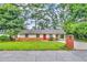 Inviting single-story home with brick accents, a bright red door, and a beautifully landscaped front yard at 3395 Spring Dr, Atlanta, GA 30360