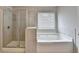 Bathroom featuring tiled shower and soaking tub next to window with blinds at 7760 Hansel Ln, Lithonia, GA 30058