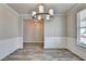 The dining room features decorative wainscoting, modern chandelier and durable wood-look flooring at 7760 Hansel Ln, Lithonia, GA 30058