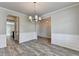 Elegant dining room featuring modern chandelier, wood floors, and view to kitchen at 7760 Hansel Ln, Lithonia, GA 30058