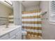 Well-lit bathroom with white vanity, toilet, and striped shower curtain at 8650 Hope Mews Ct, Sandy Springs, GA 30350