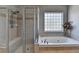 Elegant primary bathroom with jetted tub, glass shower and tile surround at 2123 Floral Ridge Dr, Dacula, GA 30019