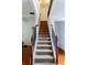 Bright staircase with carpeted steps, wooden handrails, and black iron balusters leads to the upper level of the home at 6175 Beaver Crossing Dr, Cumming, GA 30040