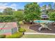An aerial view of a community playground near a pool and tennis court, surrounded by trees at 1313 Cobblestone Ln, Woodstock, GA 30189