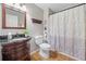 Bathroom featuring a granite vanity, decorative mirror, and shower with patterned curtain at 1313 Cobblestone Ln, Woodstock, GA 30189