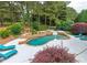 Aerial view of the backyard pool area with lounge chairs, lush landscaping, waterfall-style spa, and wooded backdrop at 100 Trotters Ridge, Fayetteville, GA 30215