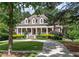 Stunning two-story home with a grand front porch, manicured lawn, and a circular driveway nestled amongst mature trees at 100 Trotters Ridge, Fayetteville, GA 30215