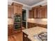 Gourmet kitchen featuring stainless steel appliances, double ovens, custom cabinets, granite countertops, and hardwood floors at 100 Trotters Ridge, Fayetteville, GA 30215